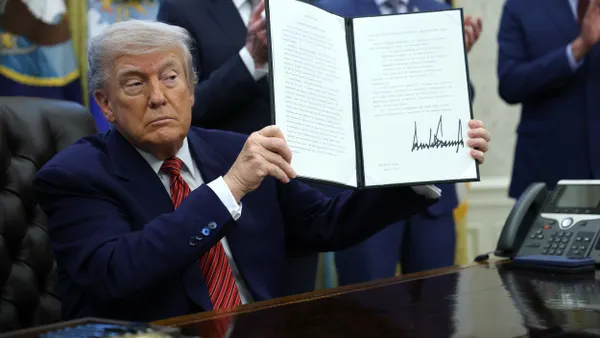 President Donald Trump holds up a signed executive order in the Oval Office of the White House