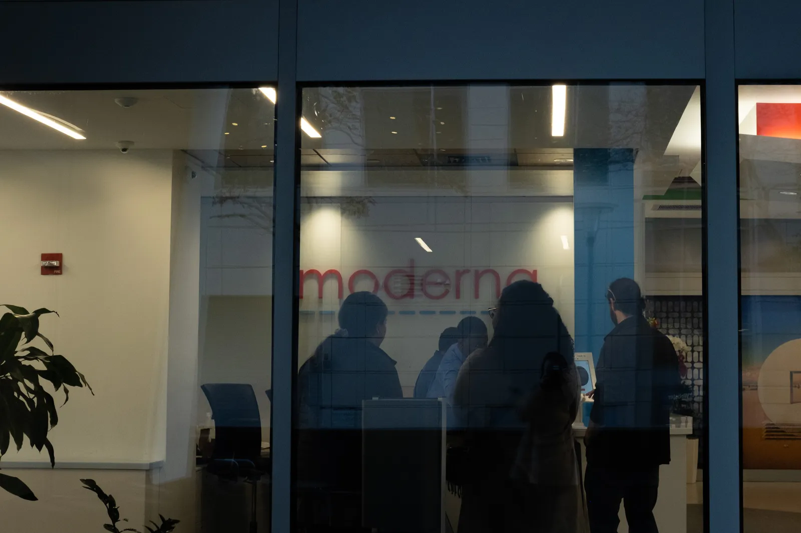 People are seen through a window at Moderna clinic.