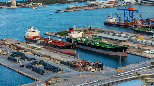 An aerial photo shows two tanker ships docked at a commercial port.