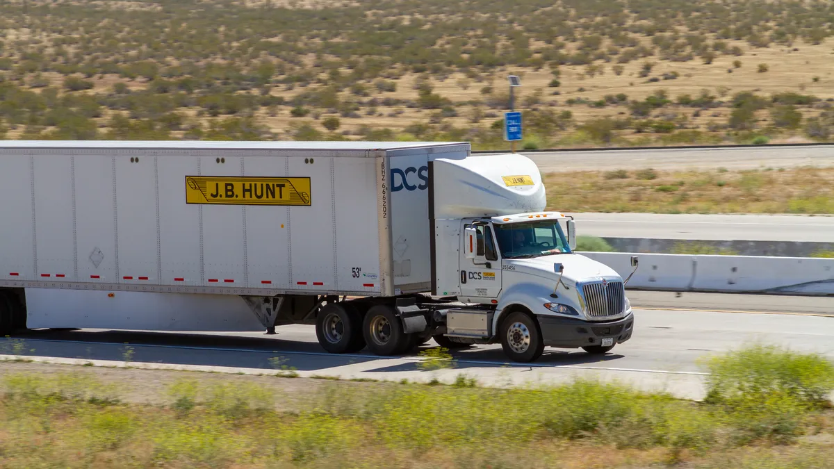 A J.B. Hunt tractor-trailer on a road surrounding by the desert.