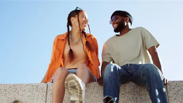 Two people talking sitting on a concrete wall