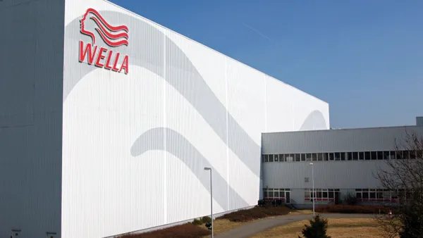 A large warehouse painted in plain white and gray waves with a Wella Company logo in red-colored font.