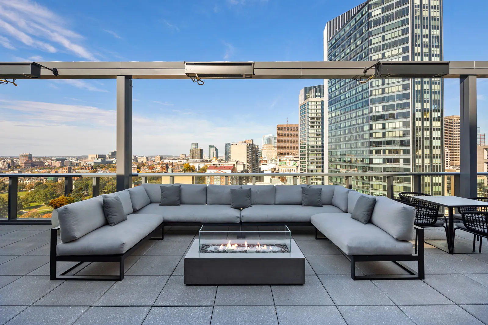 A semicircle couch surrounding a fire pit on a rooftop deck.