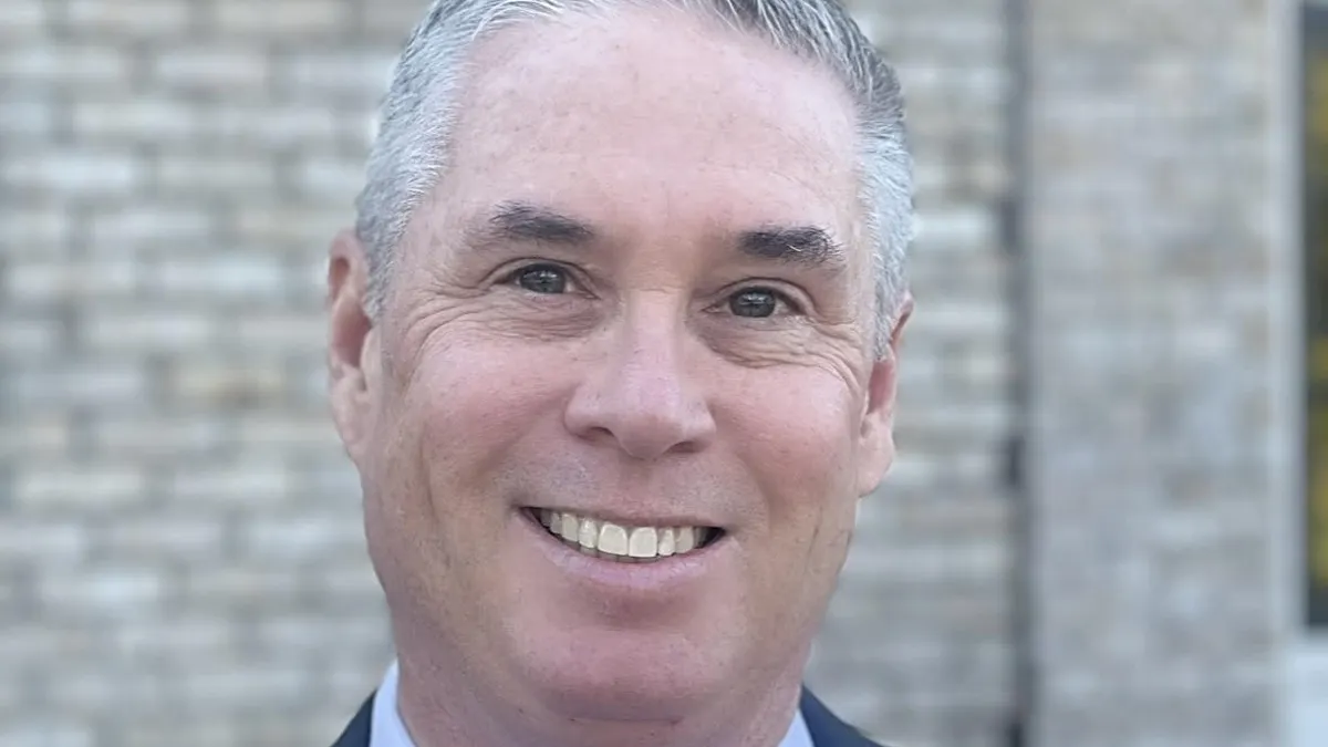 A person wearing a gray blue suit smiling