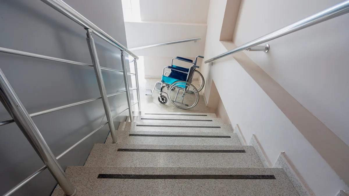 An empty wheelchair sits at a stairwell landing.