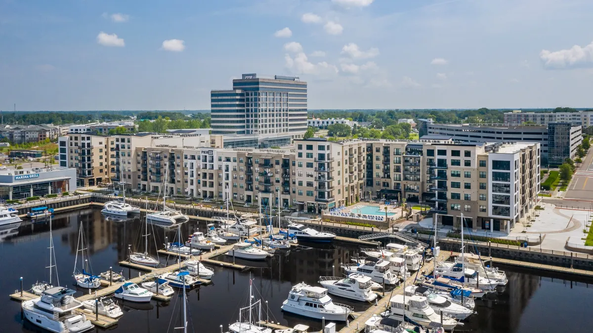 A mid-rise apartment building next to a dock full of boats.