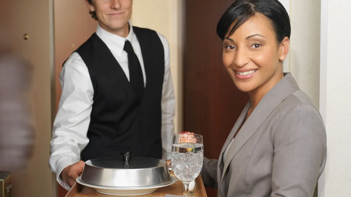 Room service waiter giving tray to smiling woman