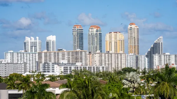 A skyline with palm trees in front of skyscraper buildings.