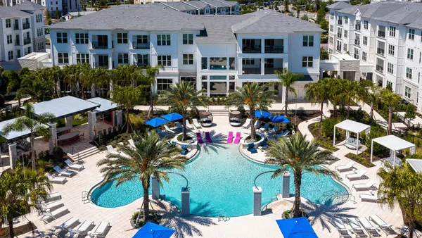 An overhead view of several low-rise white buildings surrounding a pool.