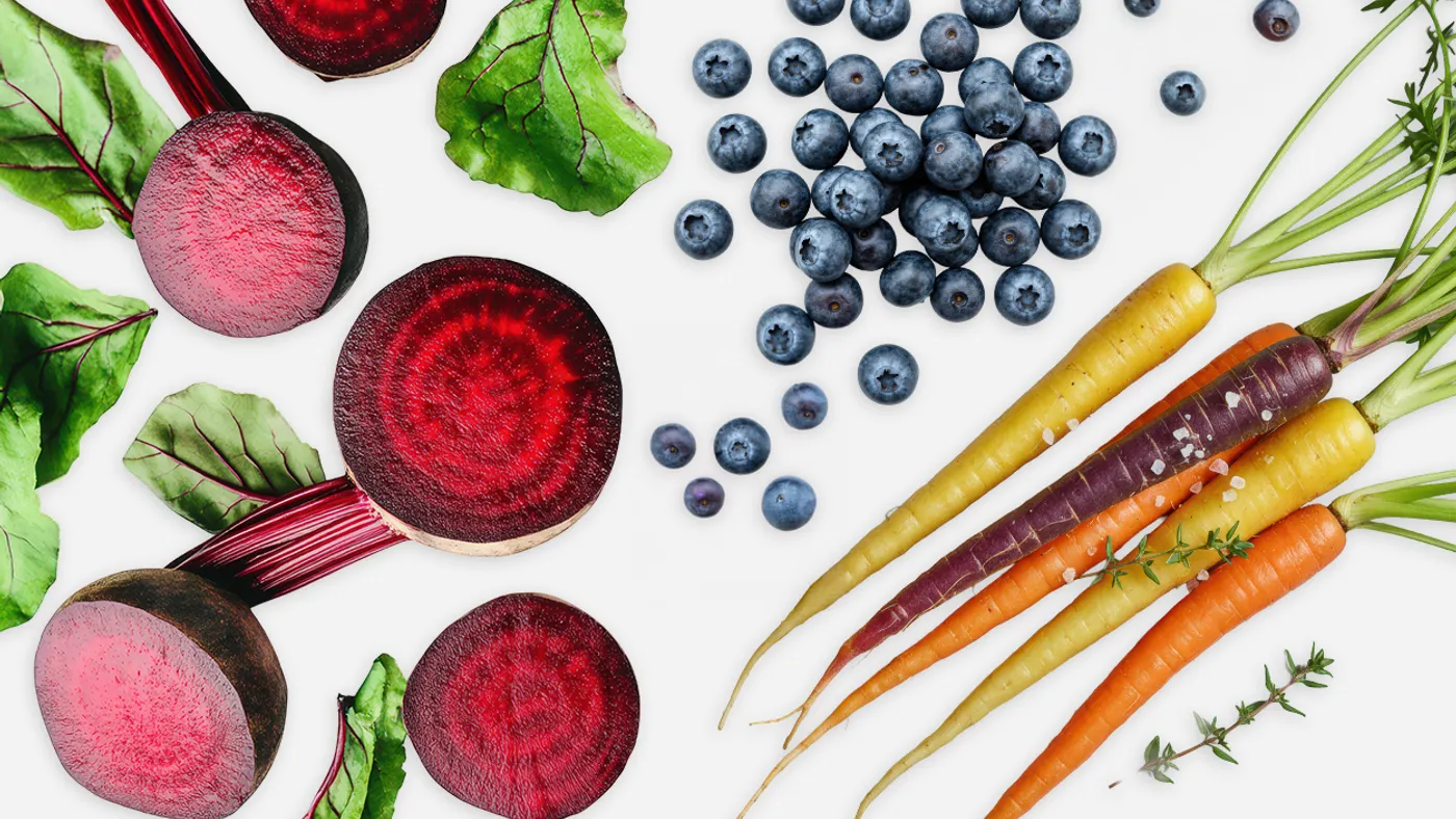 Beets, blueberries, and colorful carrots on white canvas