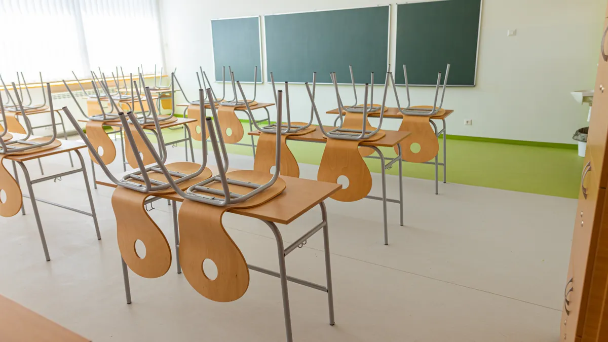 Chairs are stacked on desks in an empty classroom