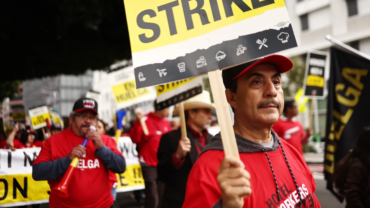 Workers hold picket signs saying 'ON STRIKE.'