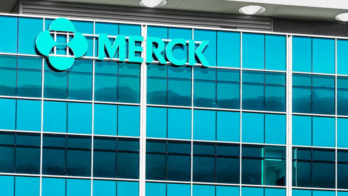 A sign spelling Merck hangs on the side of an office building