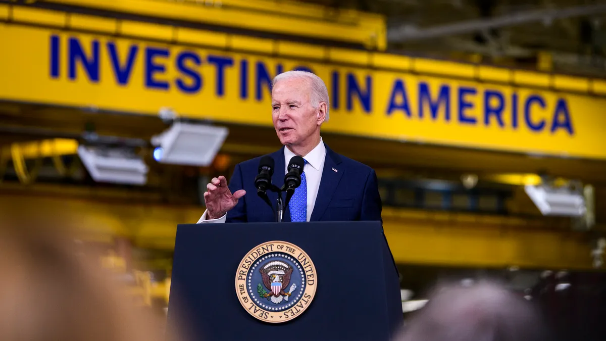 President Joe Biden in a dark blue suit and medium blue tie speaks behind a podium during a Cummins Power Generation facility visit on April 3 in Fridley, Minnesota.