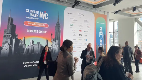 Attendees walk past The Climate Group's Climate Week NYC 2025 poster