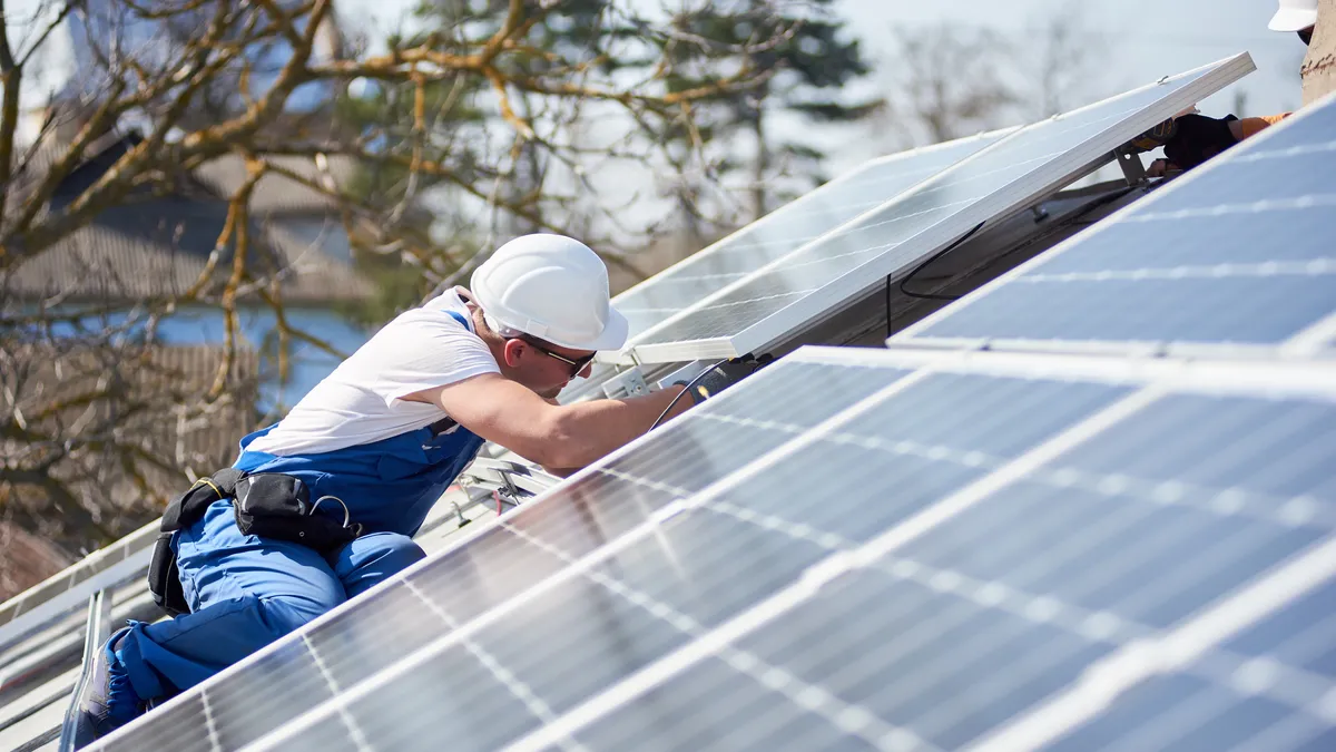 Installing solar photovoltaic panel system on roof of house.