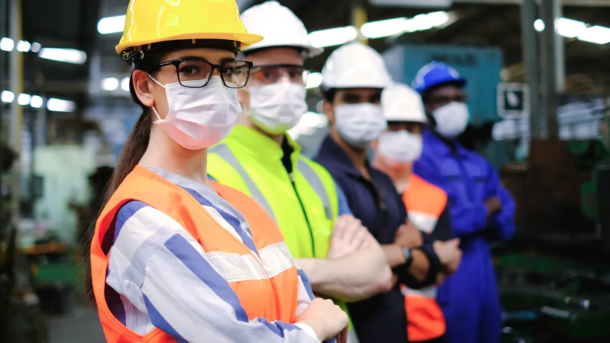 Industrial woman engineer or factory worker wearing helmet and hygiene face mask with teamwork stand in line