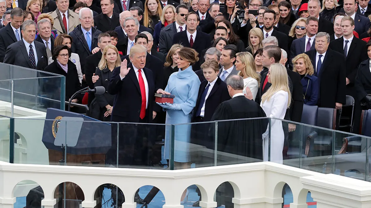 Donald Trump raises hand with a crowd of people behind him.