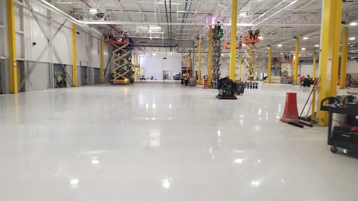 A bright open space facility with yellow poles and construction equipment at the back of the room.