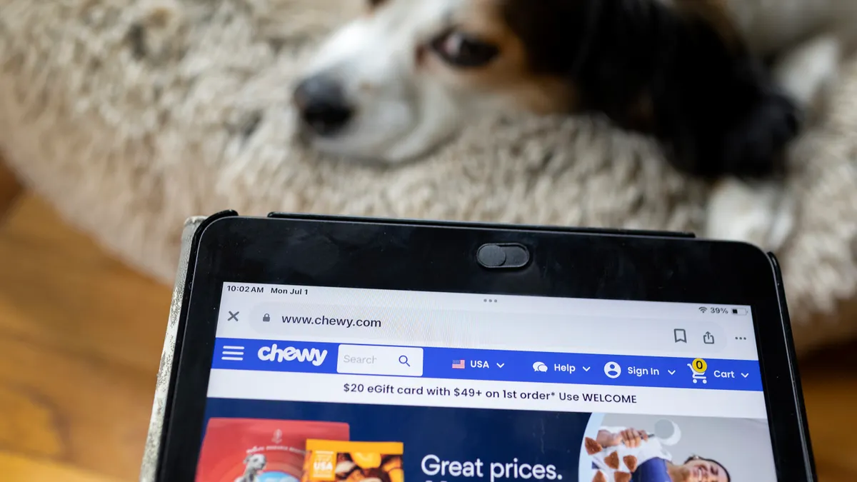 A Chewy website is displayed on a screen in front of a dog.