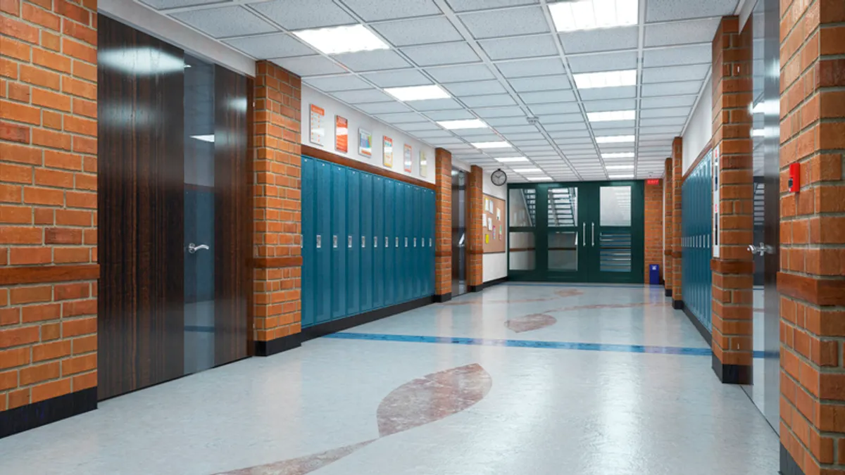 An empty school hallway with red brick and blue lockers