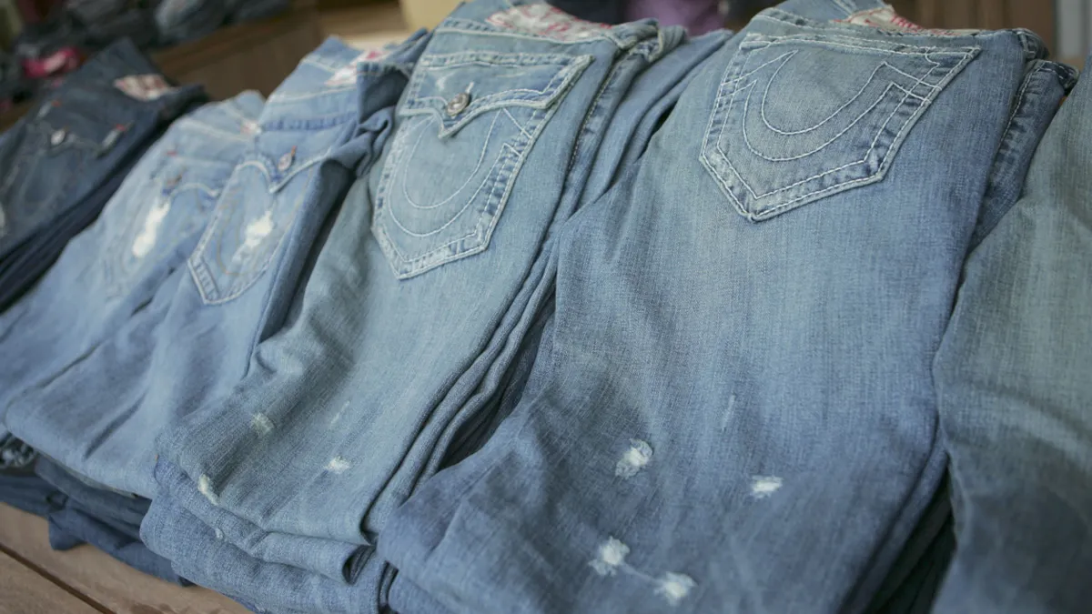 A stack of True Religion jeans for sale at a storefront.