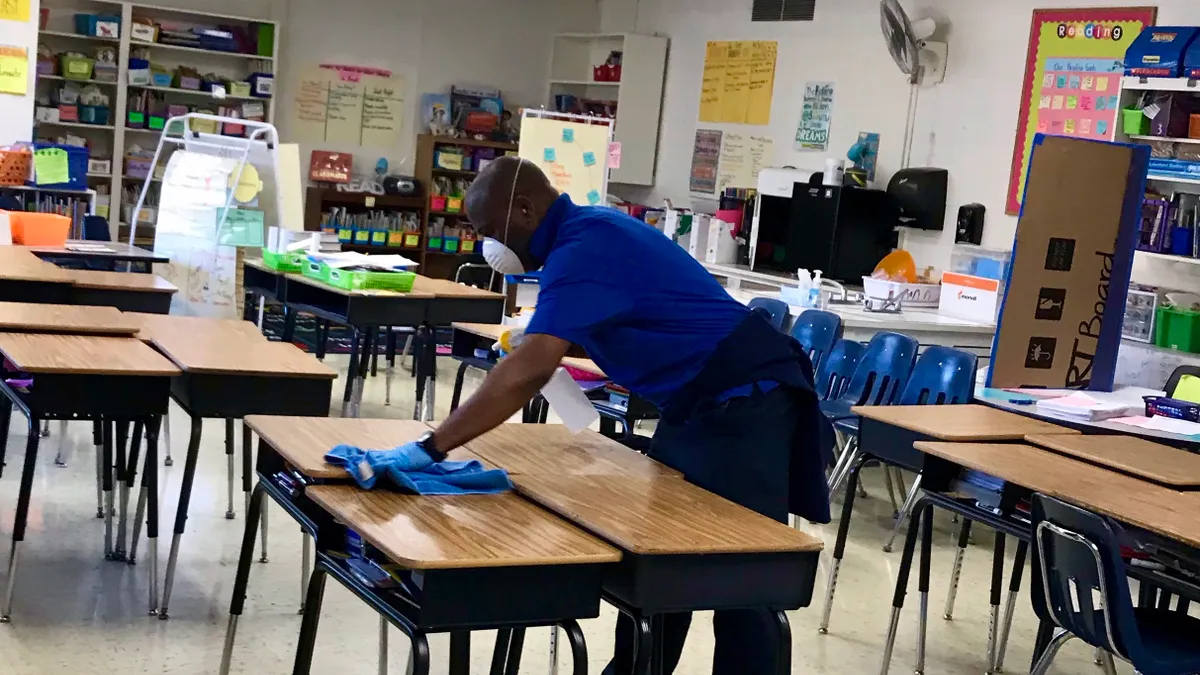 Employee in New Rochelle district applies an antimicrobial coating to desks.