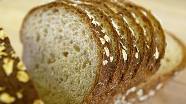 A loaf of sliced wheat bread is seen