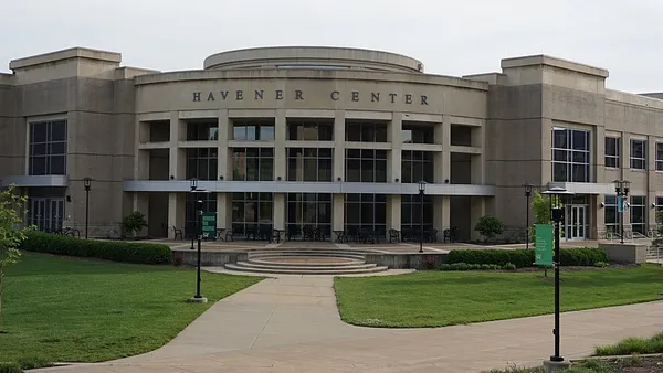 Under a gray sky, a greyish-brown stone building looms in the foreground.