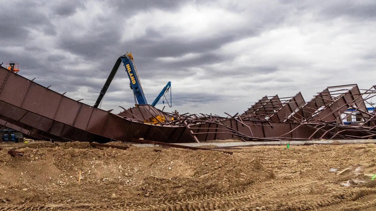 A crane stands over twisted metal debris on the ground.