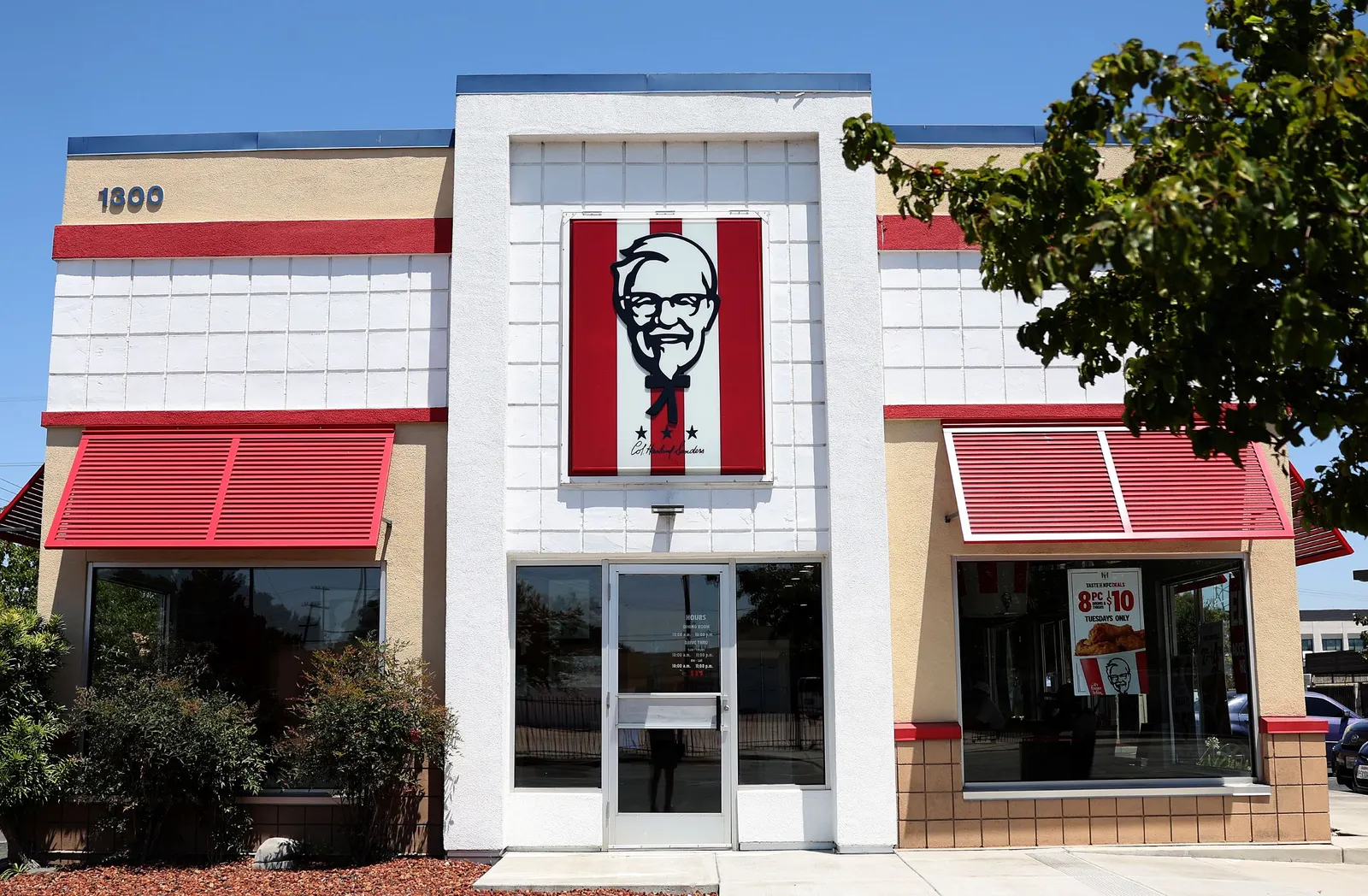 An imae of a white and beige restaurant with red awnings. The center is a logo of a person wearing glasses.