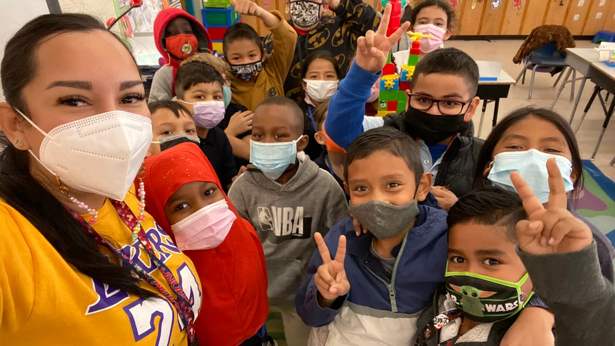 Teacher stands with elementary students in a classroom.