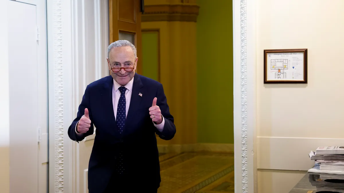 Senate Majority Leader Chuck Schumer is seen in a doorway with both thumbs up.