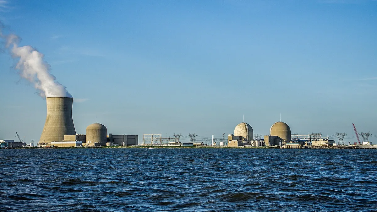 Nuclear power plant structures stand along a shoreline.