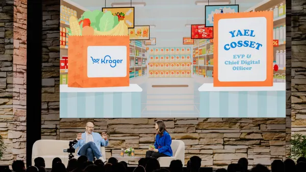 Two people sitting on a stage at a conference.