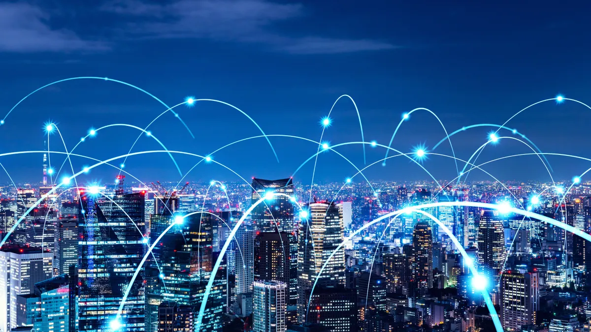 Bright city skyline at night with interconnected blue lines representing a digital network.