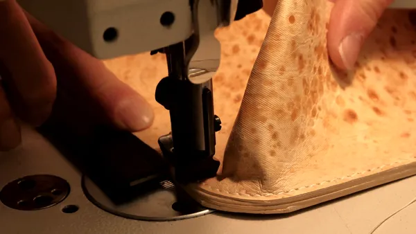 A close up of a person's hands working on a piece of leather.