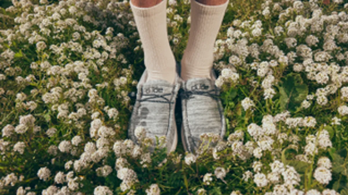 Person wearing HeyDude shoes stands on the grass.