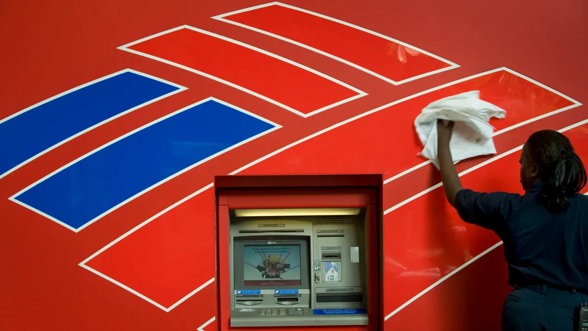 A janitorial worker polishes the Bank of America logo emblazoned on an ATM