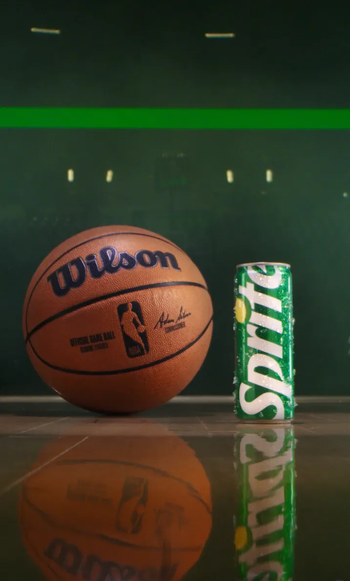 A Wilson orange basketball sits next to a Sprite can on a court
