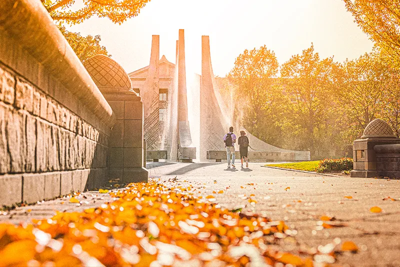 Two students walking on a college campus in the fall.