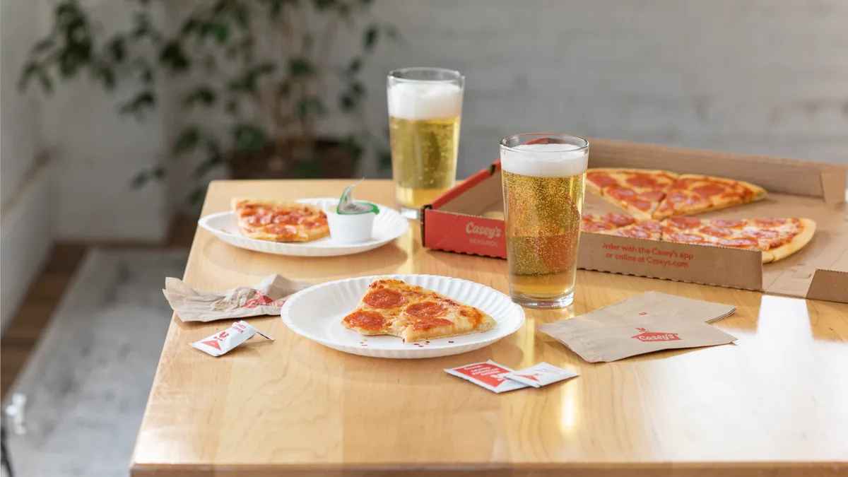 A photo of a meal consisting of pizza and beers on a wooden table.