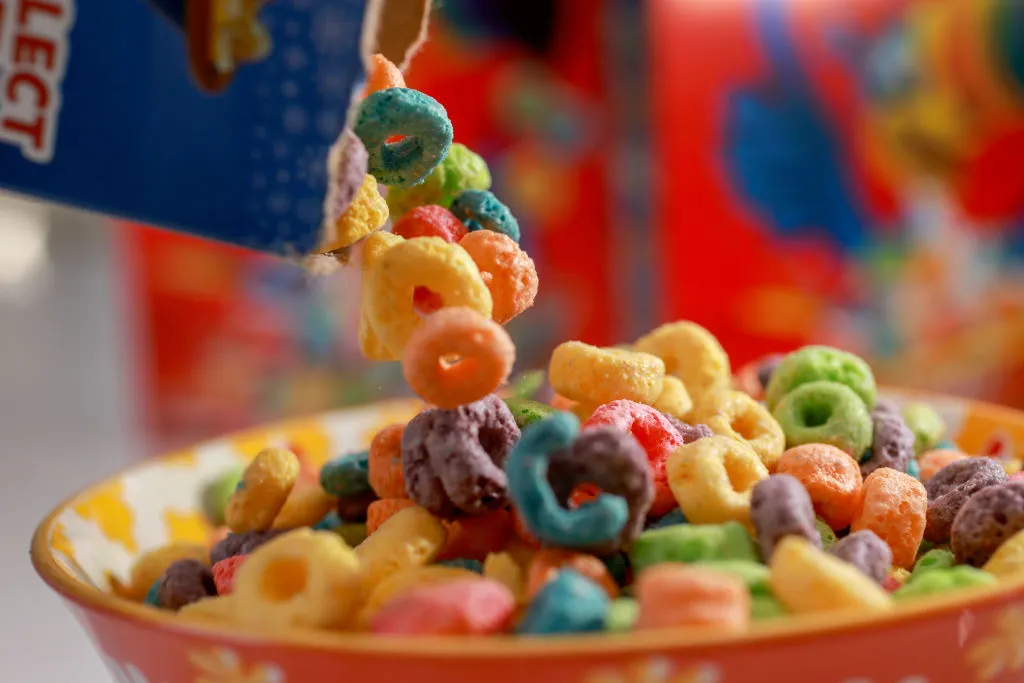 Froot Loops are being poured into a cereal bowl