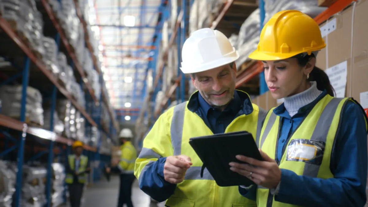 Man and woman wearing construction vest and hard hat are consulting
