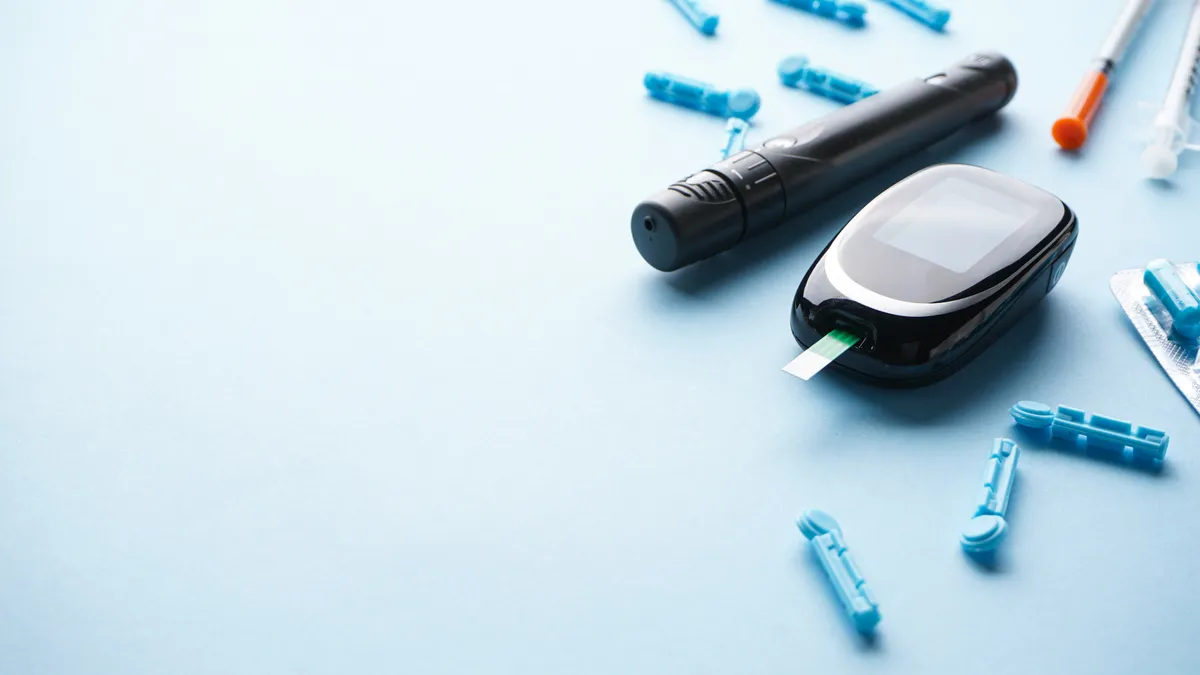 A glucometer, insulet pen and syringes on a blue background