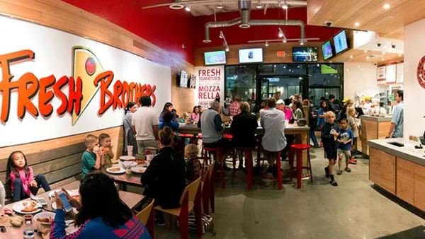 An image inside a restaurant crowded with people. The wall says Fresh Brothers."