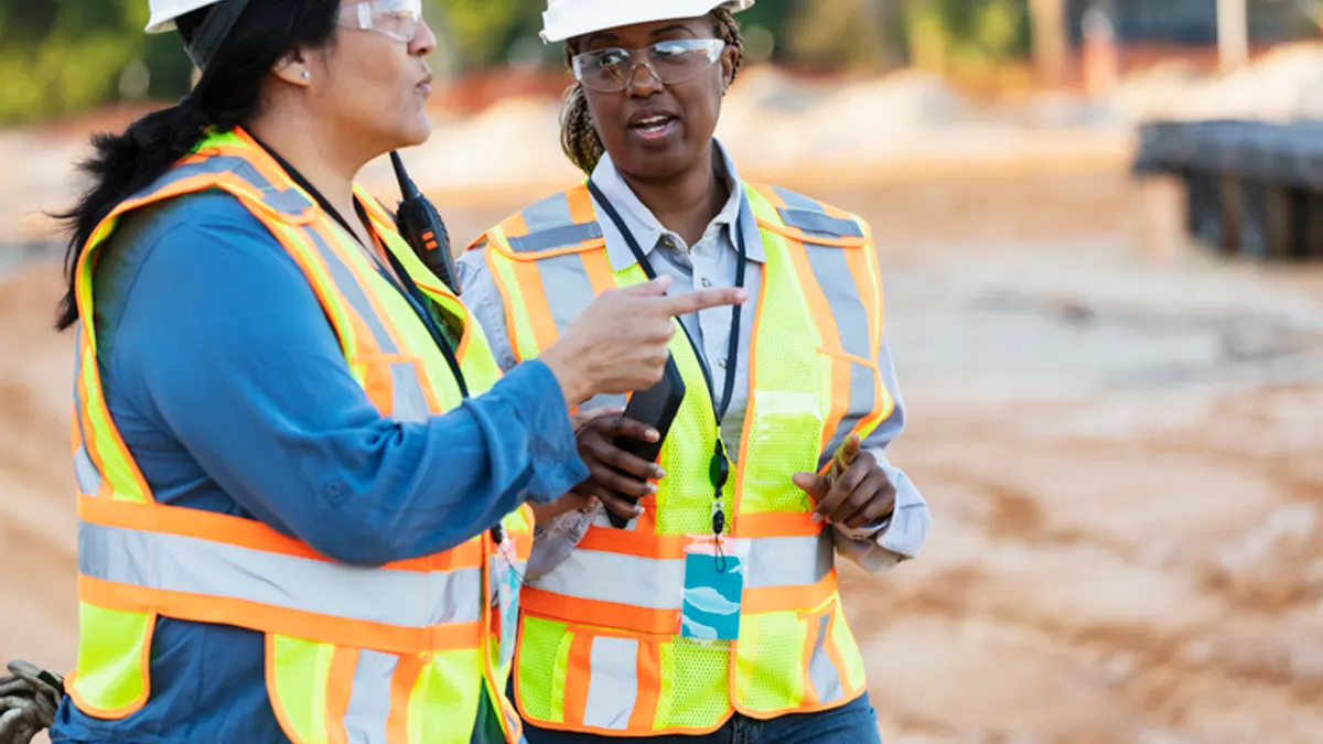 Two women construction workers discuss a project.