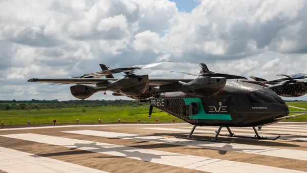 An aircraft with multiple rotors on the ground against a background of blue skies and crowds.