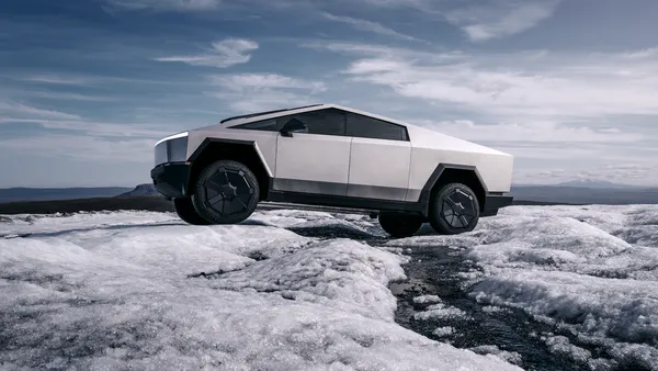 A Tesla Cybertruck travels over ice outdoors in wintery conditions.