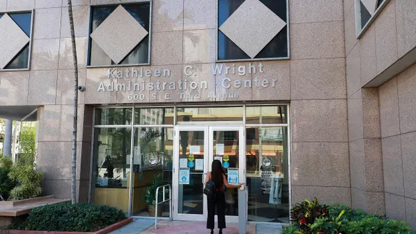 A person enters the front entrance of a building that says "Kathleen C. Wright Administration Center" above the door.
